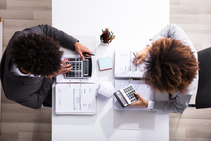 Side View Of Two Young Businesspeople Analyzing Bill In Office