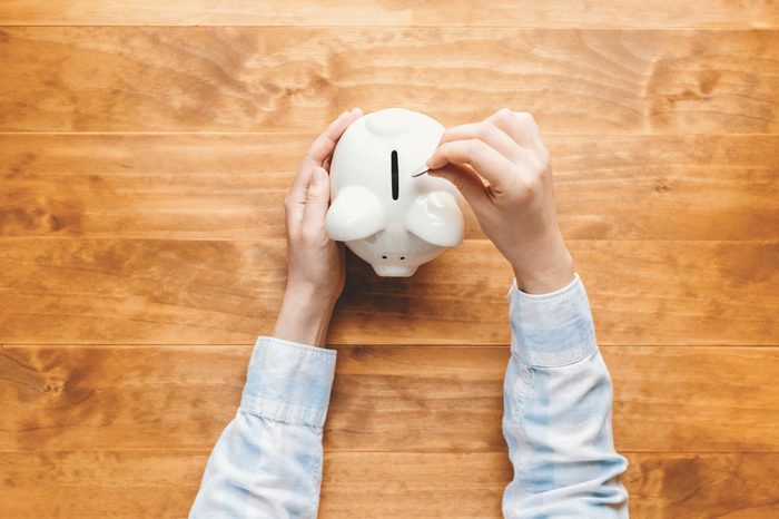 Woman holding a white piggy bank on a wooden desk