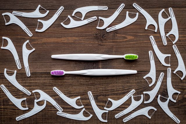 Teeth care. Floss and brush on dark wooden background top view