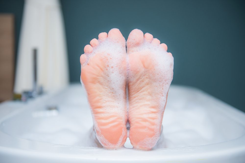 Closeup of woman's foot on the edge of a bath with foam, care