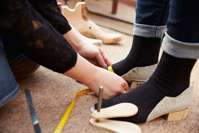 Shoemaker measuring customers feet, close up