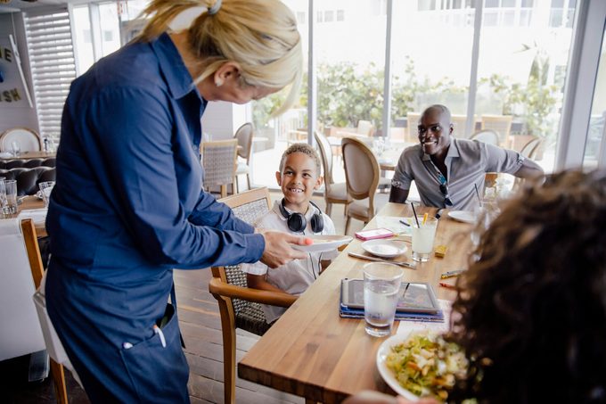 Server Bringing Food For Family In Restaurant