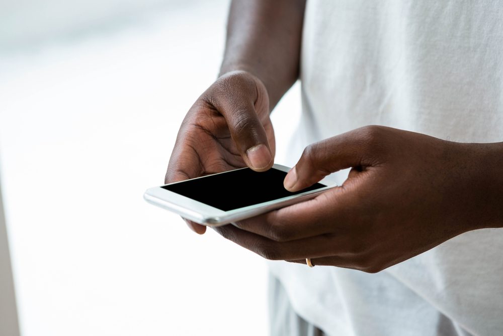 Close-up of man text messaging on mobile phone at home