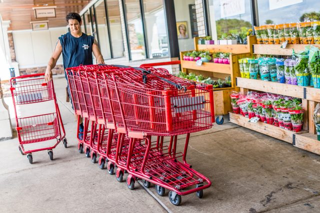 Fairfax, USA - January 18, 2017: Happy Trader Joe's employee returning shopping carts to the store outside entrance with woman customer