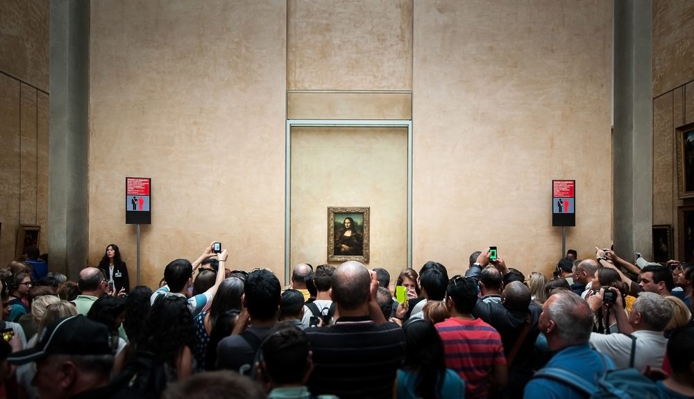PARIS, FRANCE - JUNE 18 , 2014 : A many of visitors take photos of "Mona Lisa" , by Leonardo DaVinci's at the Louvre Museum, june 18, 2014 in Paris, France.