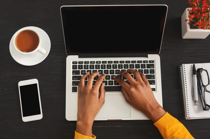 Black female hands typing on laptop. Top view of african-american woman working at office desktop with smartphone and comuter. Education, business and technology concept, copy space