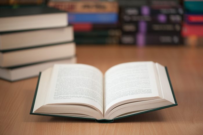 open book on library desk with books stacked in the background