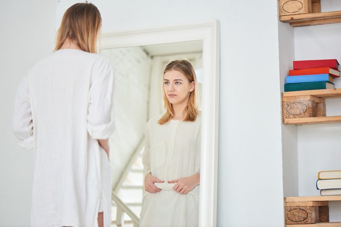 Girl unhappy with their appearance looks in the mirror