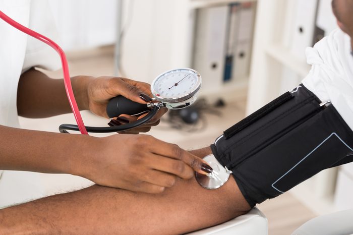 Close-up Of Doctor Measuring Patients Blood Pressure With Stethoscope