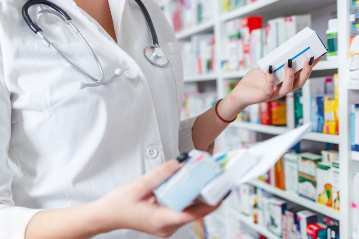 Closeup hand of woman pharmacist with prescription and medicine at drugstore