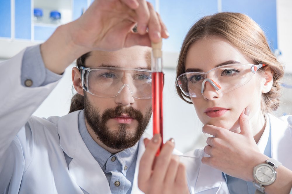 Two young scientists holding chemical sample in test tube