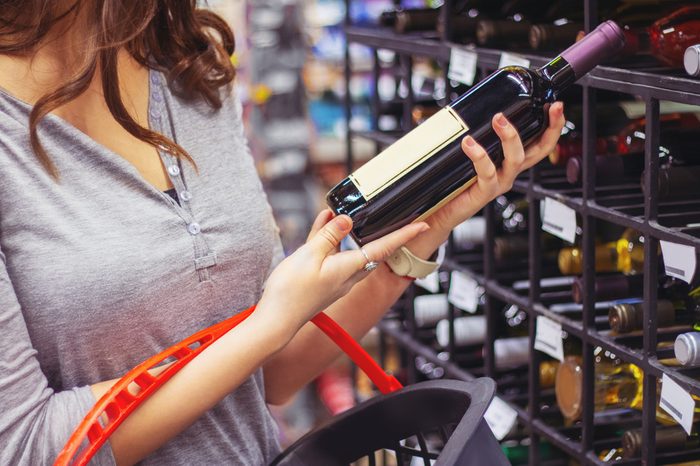 Woman buying and holding bottle of wine