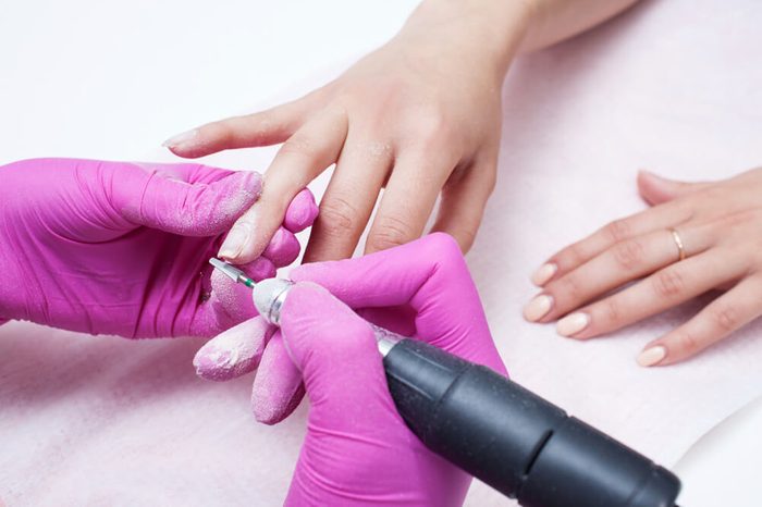 Hardware manicure. Removal of old gel varnish in the salon. Manicure master doing beauty procedure for client, closeup and top view