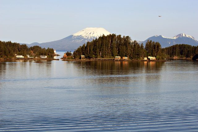 A landscape photo with water in the foreground showing sunrise on Mount Edgcome, Sitka, Alaska