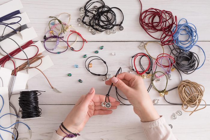 Handmade jewelry making, female hobby. Woman creating bracelet at home workshop, top view. Fashion, handicraft concept