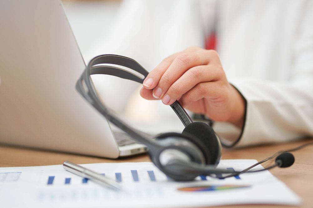 close up working call center woman hand touching headset devices for talk with customer at operation office room,contact us concept