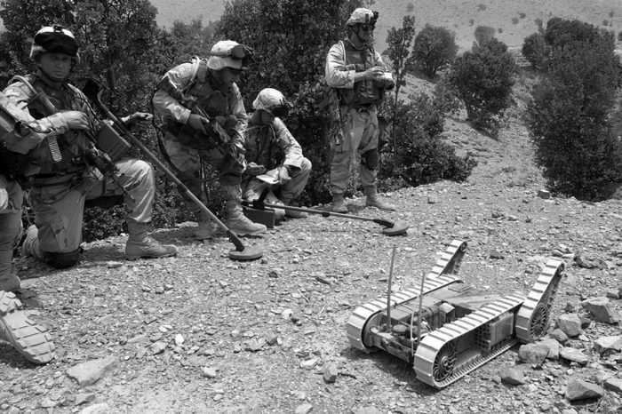 SOLDIERS MANEUVER ROBOT Land mine detectors stand by as a U.S. army soldier maneuvers "Hermes" the robot into a cave to detect mines, traps, and other unexploded ordinance as well as weapons or equipment possibly hidden by Taliban or al-Qaida fugitives in the eastern border town of Qiqay, Afghanistan, . The current war in Afghanistan marks the first use of the robots by conventional military forces in combat situations with hopes to prevent unnecessary casualties