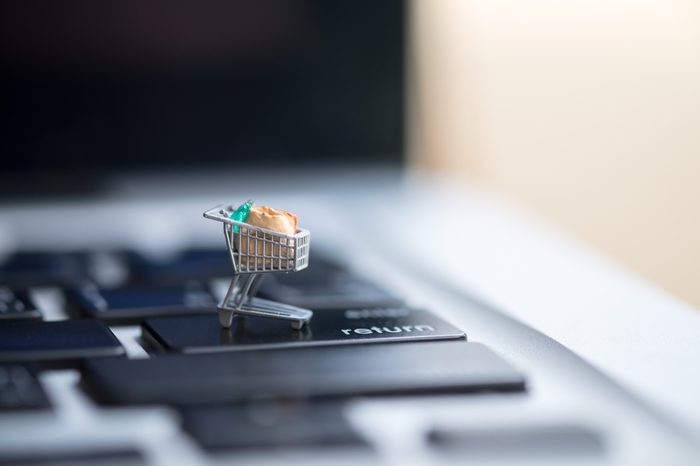 Shopping and e-commerce concept. Close up of miniature shopping cart toy figure on laptop computer