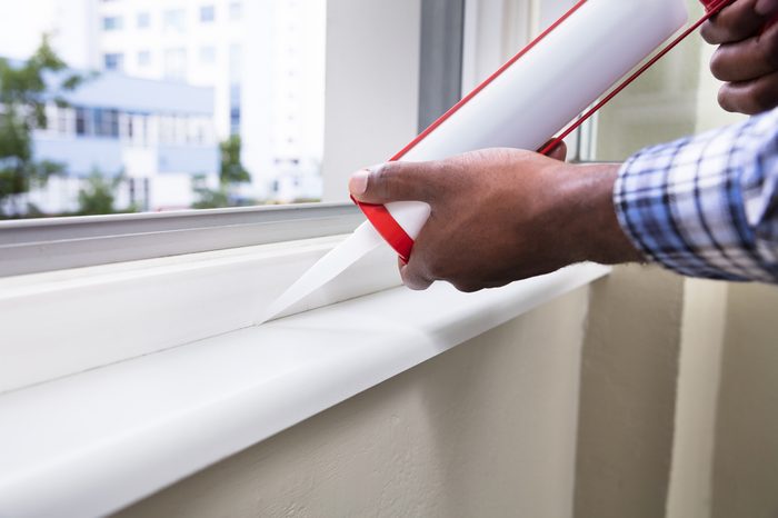 Close-up Of Person Hand Applying Silicone Sealant With Silicone Gun On Window