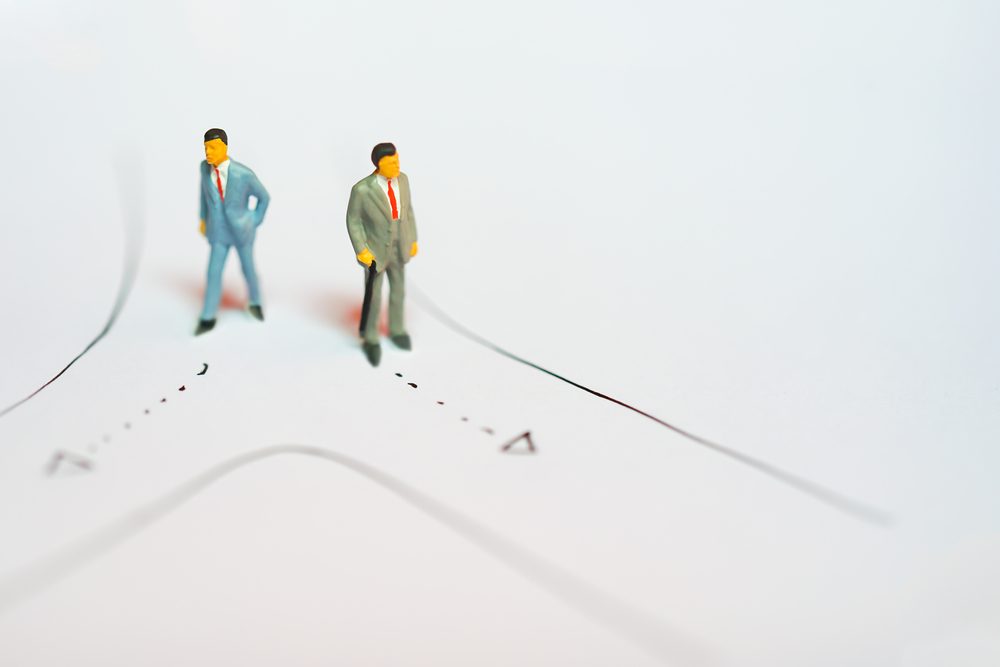 Miniature figures of Two business man standing on road selecting way to walk as decision making on white notebook paper drawing line with copyspace - business success backgroun concept