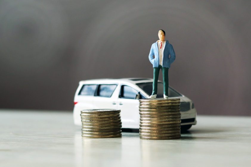 miniature people. The man standing on top of the coins and the car behind them.