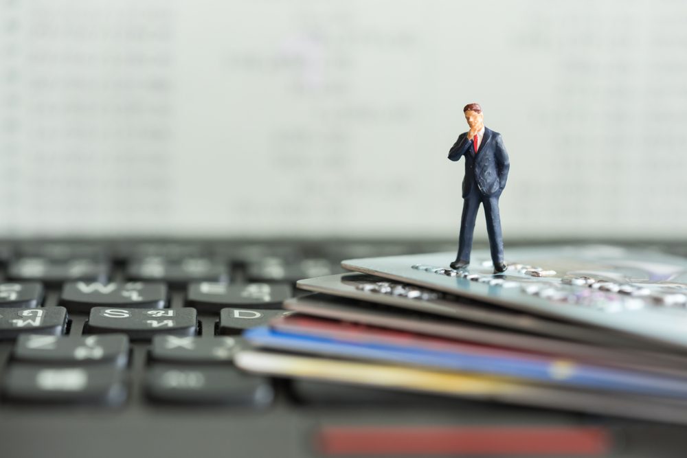 Shopping and e-commerce concept. Miniature people : Close up of miniature businessman on smart card and laptop keyboard.