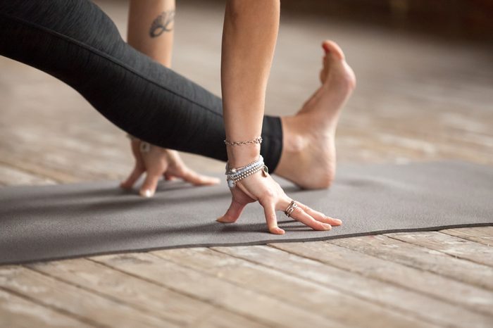 Young woman practicing yoga, doing Half splits exercise, Ardha Hanumanasana pose, working out, wearing sportswear, black pants, indoor close up, yoga studio. Healthy lifestyle concept