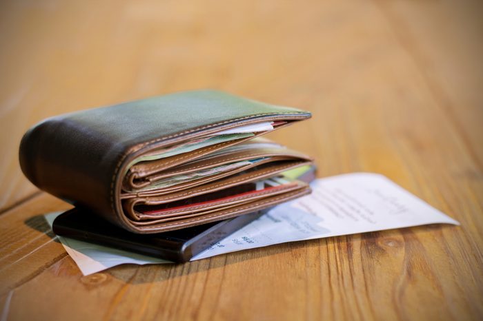 Soft tone of Money and credit card in a leather wallet on wooden table and bill slip background