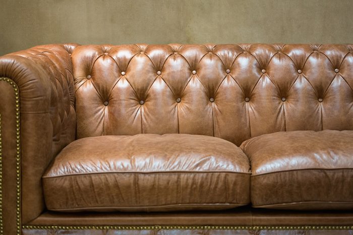 Vintage brown leather sofa with grunge gray wall living room.