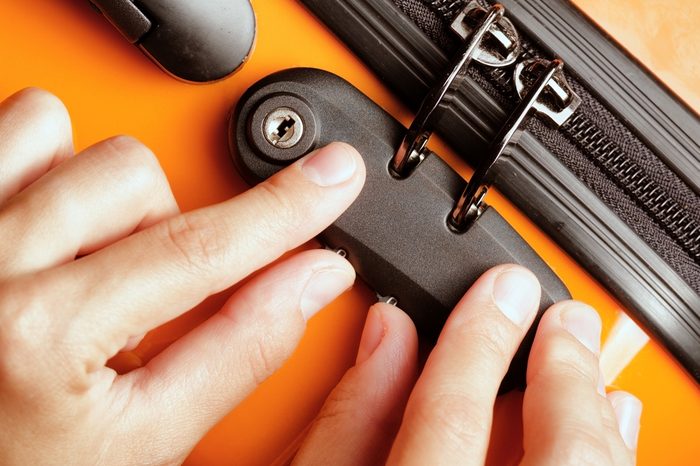 Woman locked her luggage in the orange suitcase.