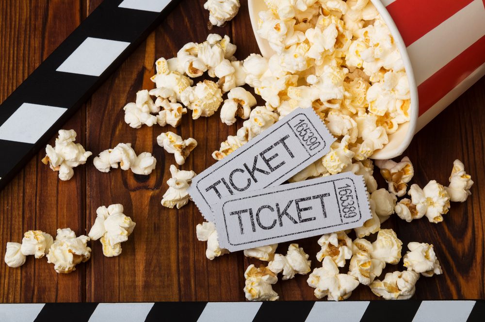 Clapper board, spilled popcorn and movie tickets on a background of boards