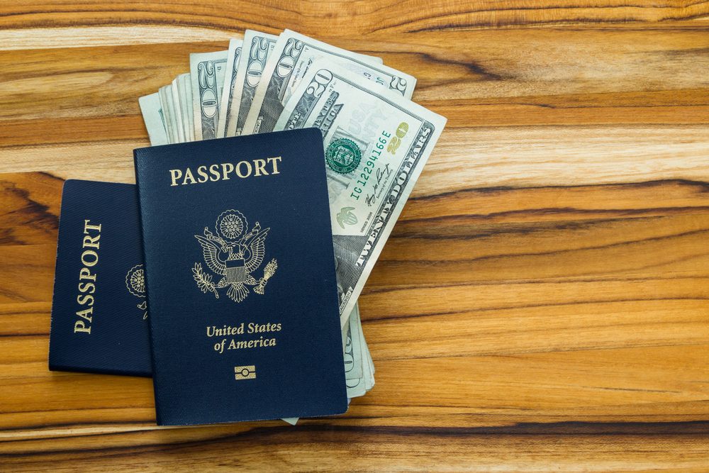 close up of two american passports and cash money on a wooden table for a travel concept