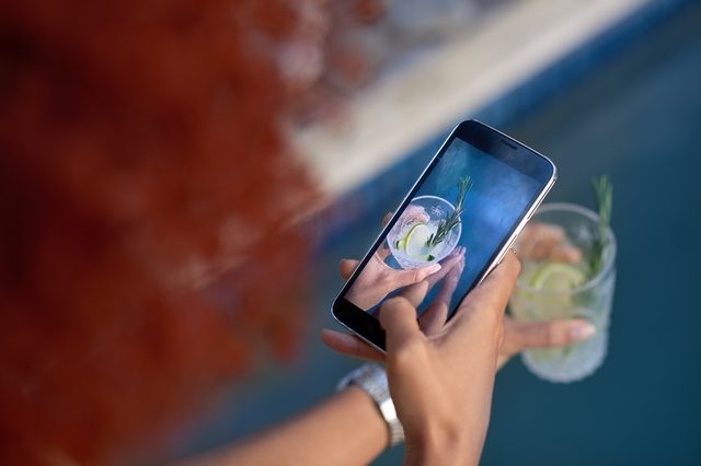 Summertime fun cocktails by the pool, woman hands take photograph shot with smartphone mobile cell phone