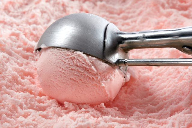 Strawberry ice cream scooped out of container
