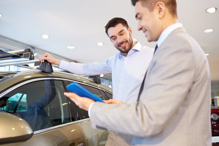 auto business, car sale, technology and people concept - happy man and car dealer with tablet pc computer in auto show or salon