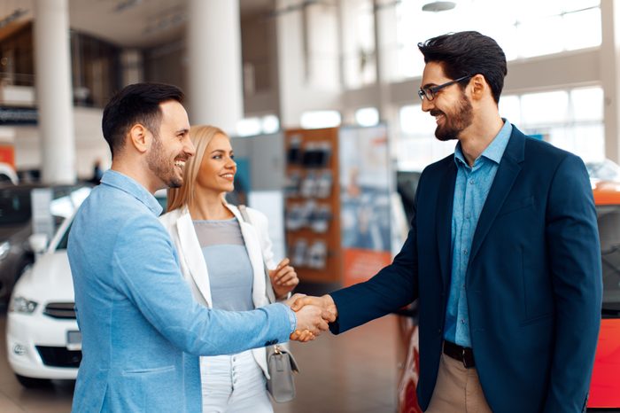 Young couple shaking hands after a successful car buying