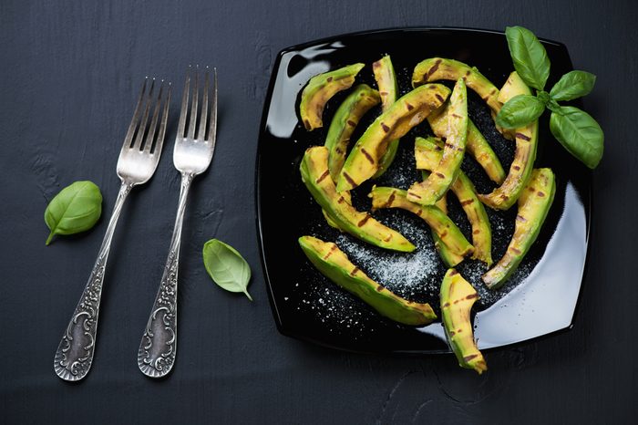 Grilled avocado slices with sea salt on a plate, view from above