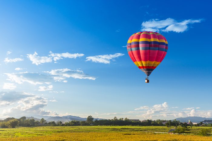 hot air balloon over the green paddy field. Composition of nature and blue sky background