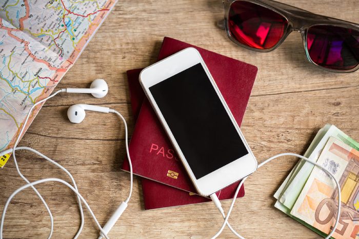 Preparation for travel, cell phone, money, passport, road map on wooden table