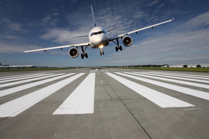 Landing aircraft low over the runway with stretched landing gear