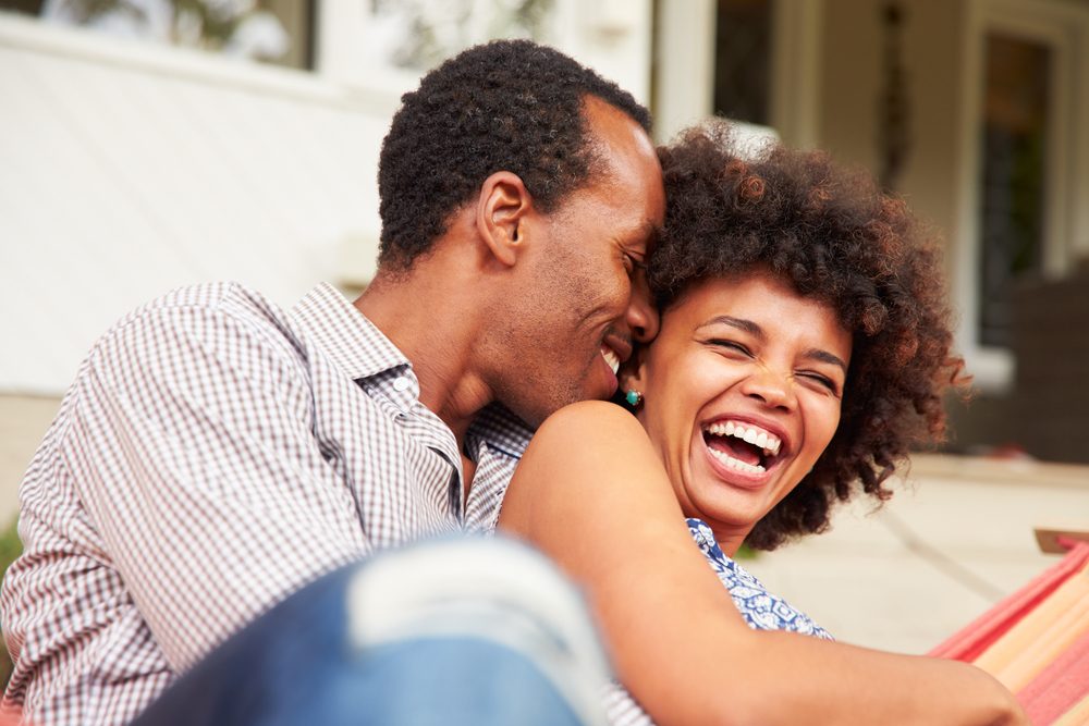 Laughing couple cuddling in a hammock