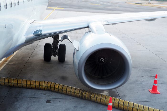 An image of the airplane engine and main land gear with an air-condition supply positioned with the traffic cones.