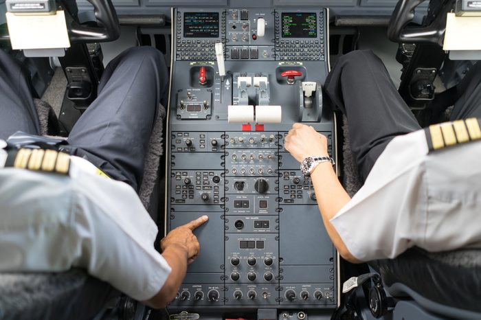 view of business jets cockpit. Two pilots operate a switches of aircraft system prior to departure.