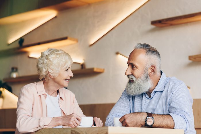 side view of senior couple having conversation while drinking coffee together in cafe