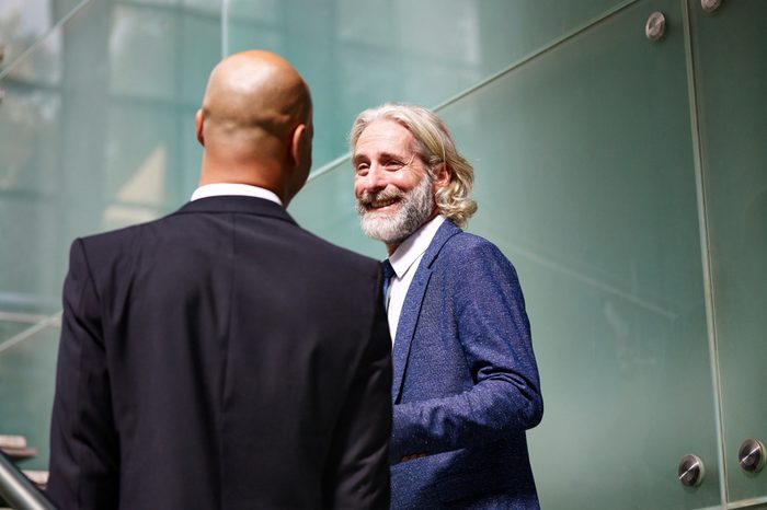 caucasian and latino corporate executives having a conversation while ascending stairs in modern office building.