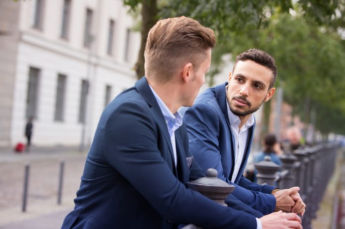 two handsome businessmen standing outside and having a conversation