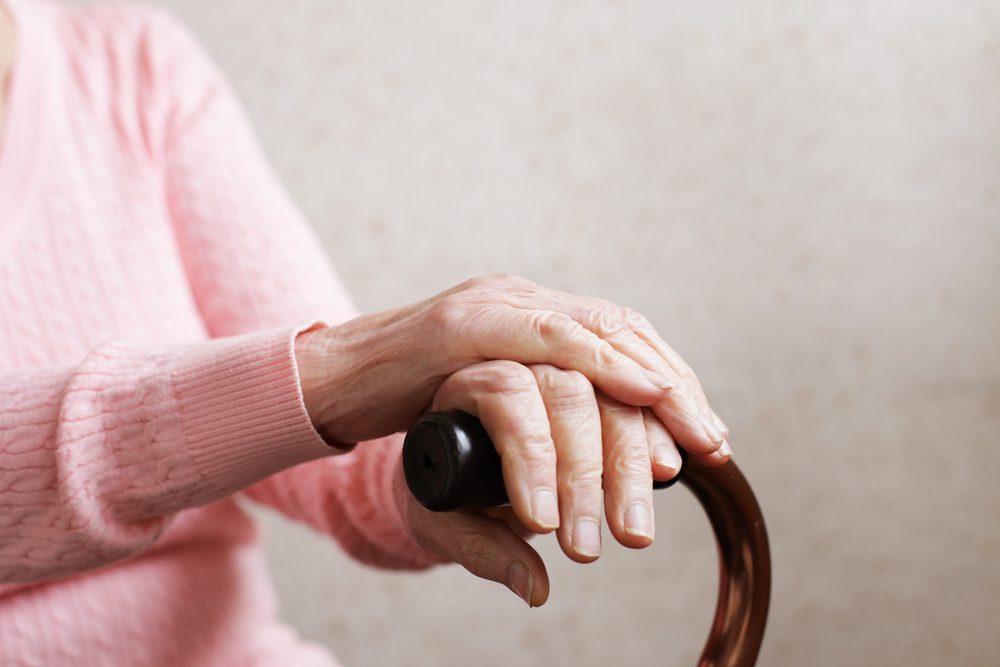 Hands of an old woman with a cane