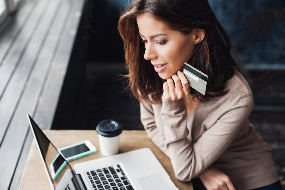 Young woman holding credit card and using laptop computer. Online shopping concept