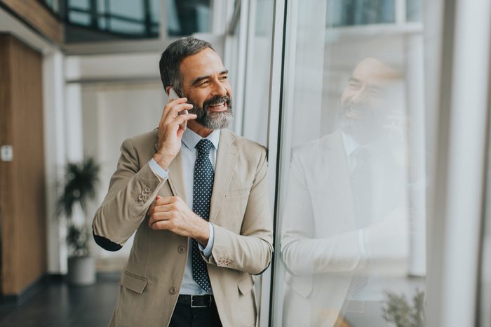 Handsome mature businessman with mobile phone in the office