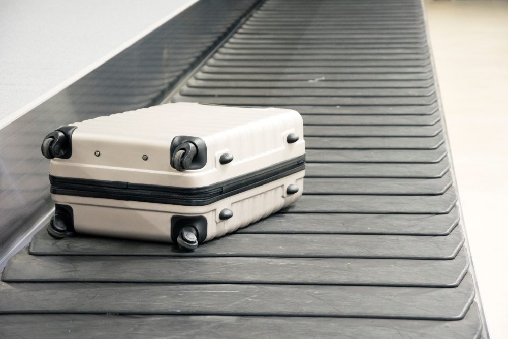 Wheeled suitcase on a luggage belt at the airport terminal.